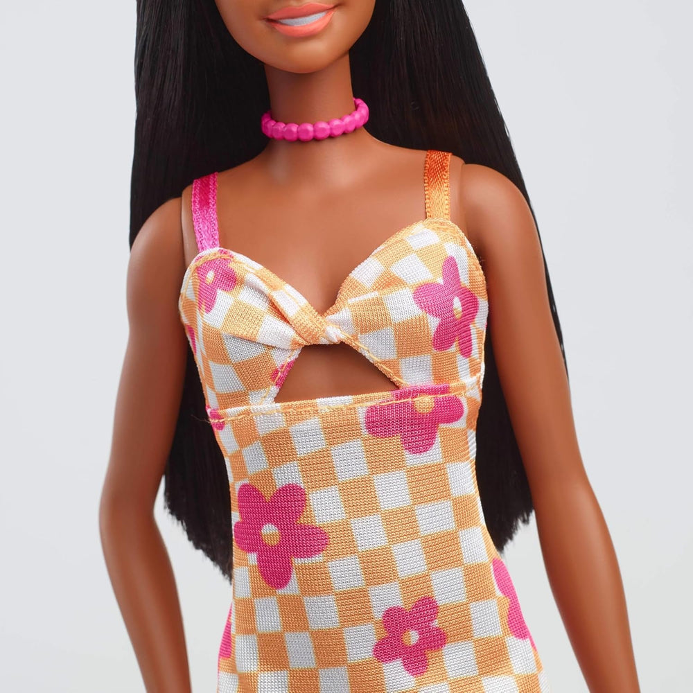 Păpușa Barbie Fashionistas nr. 233 cu păr negru, rochie midi portocalie în carouri cu flori roz, colier și sandale, HYT91