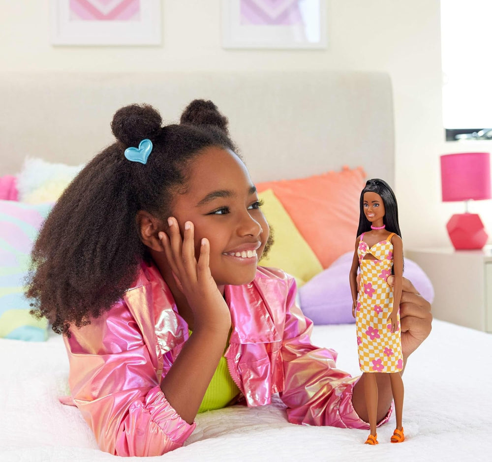 Păpușa Barbie Fashionistas nr. 233 cu păr negru, rochie midi portocalie în carouri cu flori roz, colier și sandale, HYT91